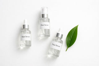 Three face serum bottles with droppers and a green leaf on a white background