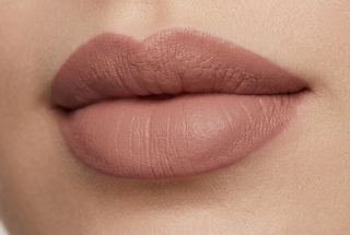 Close-up of a person's lips with a soft pink lipstick on a neutral background