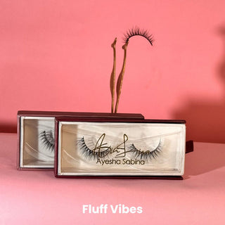 Eyelash packaging with lashes displayed on a pink background, featuring the brand 'Ayesha Sabina'.