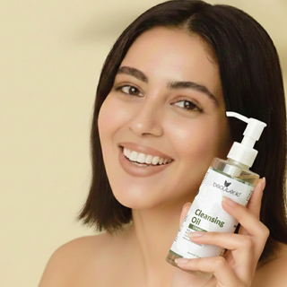 Woman holding a bottle of cleansing oil with a beige background