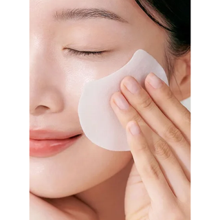 Person applying a patch to their face with a neutral background