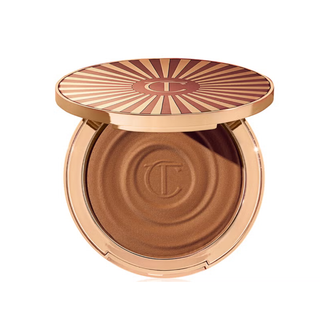 Compact powder with sunburst design on lid against a white background