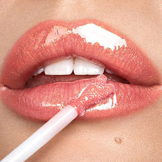 Close-up of a person applying lip gloss to their lips.