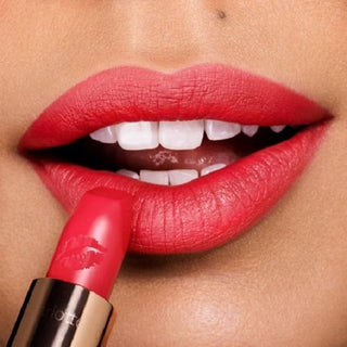 Close-up of a person applying red lipstick to their lips.