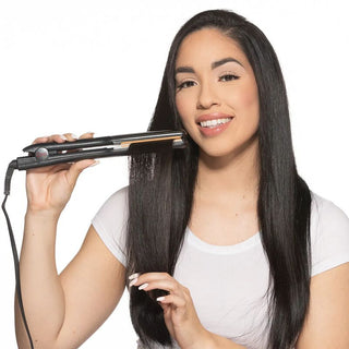 Woman using a hair straightener on her long hair against a white background