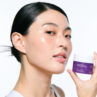 Woman holding a purple skincare product with a white background