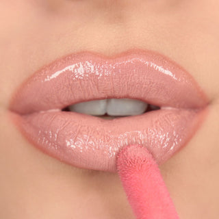 Close-up of a person applying pink lip gloss with a brush.