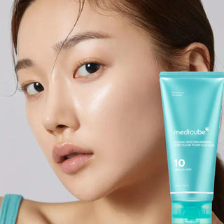 Woman holding a tube of Medicube cleanser against a neutral background
