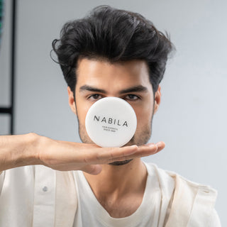 Person holding a white container with 'Nabila' branding in front of their face against a neutral background