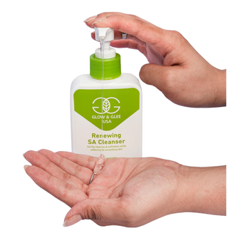 Hand holding a bottle of Glow & Glee Renewing SA Cleanser with a green pump.