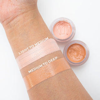 Cosmetic cream swatches on a wrist with labeled color ranges and open containers.
