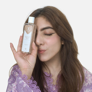 Woman holding a bottle of skincare product against a plain background
