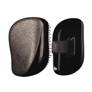 Black hairbrush with textured head and comb section on a white background