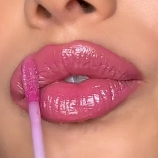 Close-up of a person applying pink lip gloss with a brush.