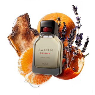 Perfume bottle labeled 'Awaken Distilled' surrounded by oranges and lavender on a white background