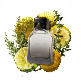 Perfume bottle labeled 'Awaken' surrounded by lemons and herbs on a white background