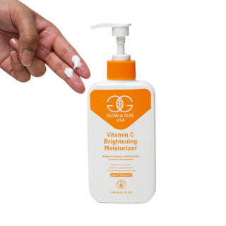 Glow & Glee Vitamin C Brightening Moisturizer bottle with a hand holding it on a white background