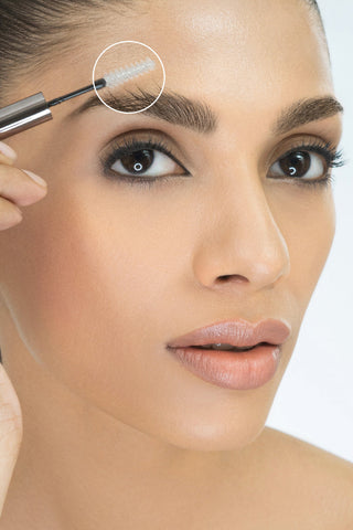 Woman applying mascara to her eyelashes with a close-up of the brush.