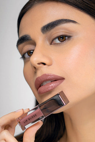 Woman holding a lip gloss with a neutral background