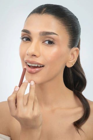 Woman applying lipstick with a neutral background